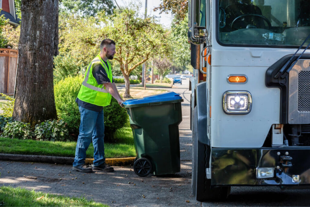 Worker rolling trash bin curbside